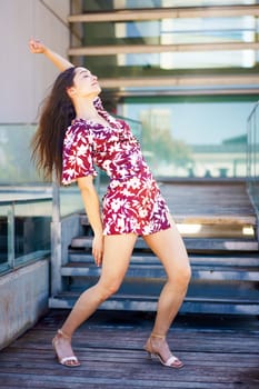 Vertical photo of a modern female hispanic adult dancer performing free style raising the arm in the street