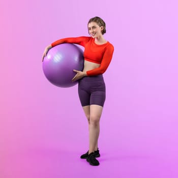 Full body length gaiety shot athletic and sporty young woman with fitness exercising ball in standing posture on isolated background. Healthy active and body care lifestyle.