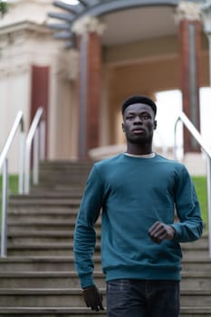 A young black man walking down the stairs of a park in Bilbao.