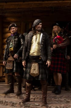 A lord of one of the Scottish clans with his people. Piper. Scotland