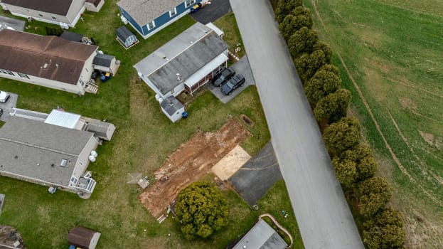 Aerial View Of Small Residential Area With Mobile, Manufactured, Prefab Homes, Driveways, And Parked Cars On A Quiet Street, Highlighting Neat Lawns, Roofs, And A Mixture Of Trees And Grass In A Calm Suburban Neighborhood.