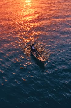 A man is in a canoe on a lake at sunset. The sky is orange and the water is calm