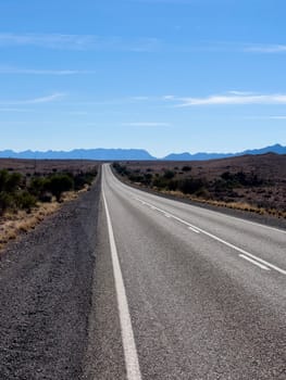 A long, deserted road stretches towards distant mountains in Ikara Flinders Ranges