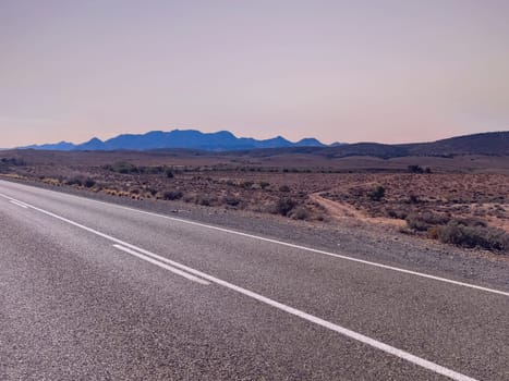 A long, deserted road stretches towards distant mountains in Ikara Flinders Ranges