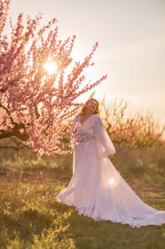 Woman blooming peach orchard. Against the backdrop of a picturesque peach orchard, a woman in a long white dress enjoys a peaceful walk in the park, surrounded by the beauty of nature