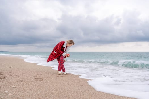 Lady in plaid shirt holding a gift in his hands enjoys beach with Christmas tree. Coastal area. Christmas, New Year holidays concep.