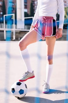 legs of an unrecognizable female football player stepping on a soccer ball in a urban court, concept of sport and active lifestyle