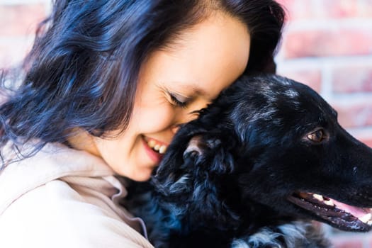 Happy brunette lady in a casual wear hugging mudi pet dog, studio background.