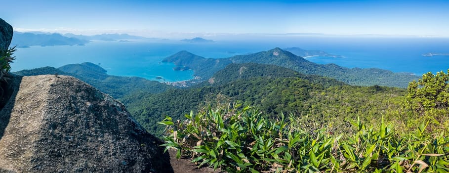 Panoramic view of lush green mountains with a blue ocean backdrop.