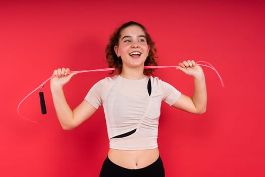 Cute teenage girl with a jumping rope looking at camera and smiling while having workout