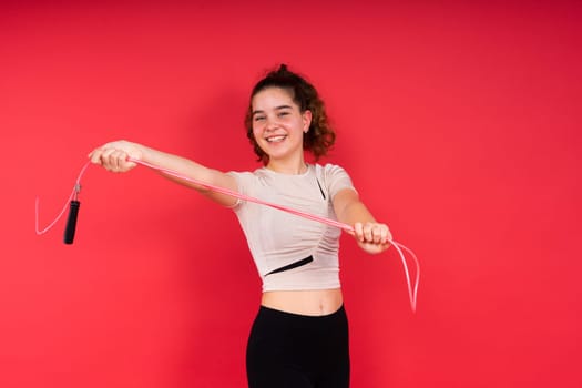 Cute teenage girl with a jumping rope looking at camera and smiling while having workout