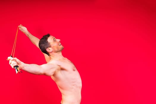 Full length portrait of a young man exercising with a skipping rope and looking at camera