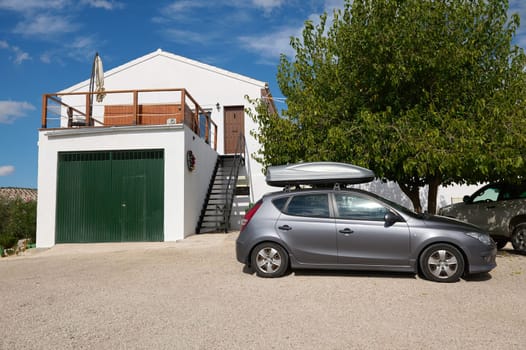 A contemporary white house with a green garage door, a balcony, and a silver car parked outside under a clear sky. Perfect for depicting suburban life.