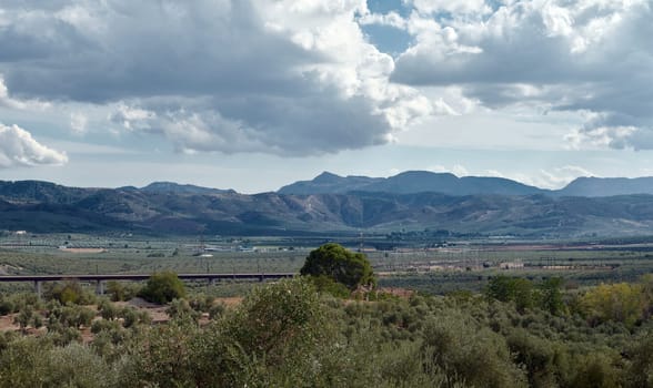 Beautiful landscape showing a vast view of mountains, green fields, and a cloudy sky. Perfect for nature and travel imagery.