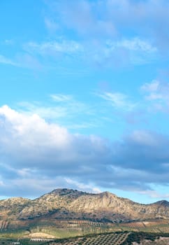 Scenic view of a mountainous landscape with clear blue sky, fluffy clouds, and lush greenery. Ideal for backgrounds and nature themes.