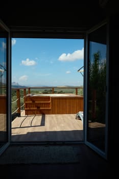 Inviting outdoor deck with a hot tub and scenic view through open doors, creating a tranquil and relaxing atmosphere.