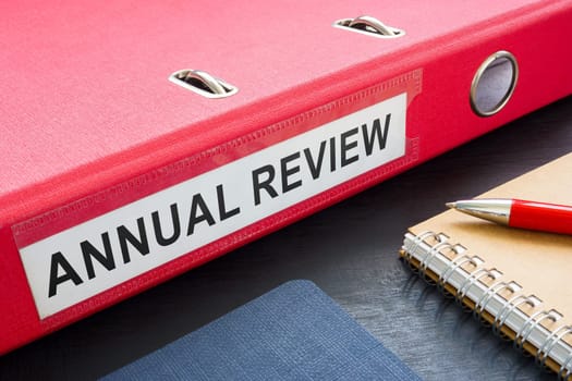 Red folder with annual review and notebooks.