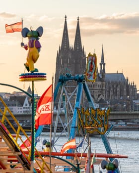 COLOGNE, GERMANY - APRIL 19, 2023: City skyline with cathedral with funfair in the foreground during sunset on April 19, 2023 in Cologne, Germany