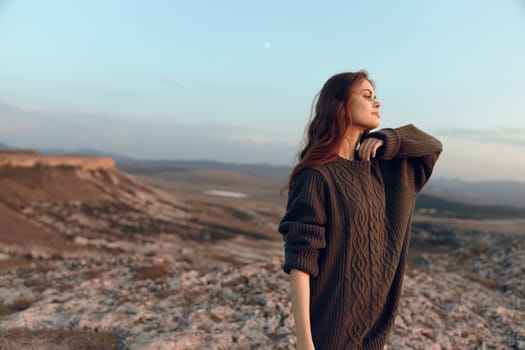 majestic woman in sweater stands on mountain peak under moonlit sky, embracing the beauty of nature