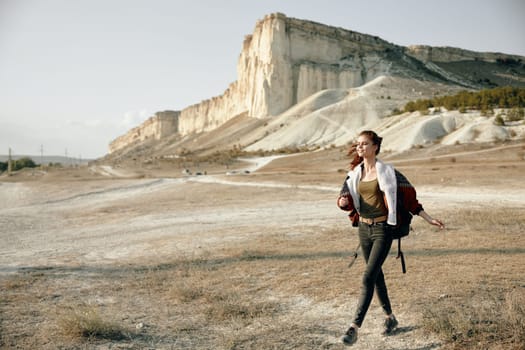 Woman in black leggings and red jacket standing confidently against majestic mountain backdrop