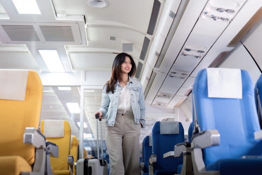 A young female tourist with a suitcase walks through the aisle of an airplane, ready for her travel adventure. The airplane cabin is modern and well lit.