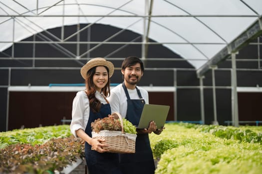 A couple working together in a greenhouse, showcasing modern agriculture techniques with fresh produce and digital tools.
