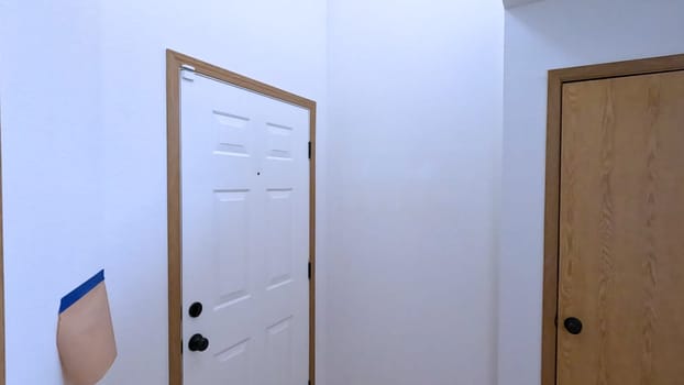 A home renovation project featuring a wooden door and a staircase with protective coverings. The area is prepped for painting or additional construction work, showcasing the initial stages of home improvement.