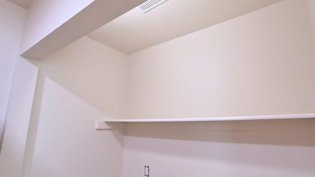 A utility room in the middle of renovation, showcasing exposed plumbing and electrical outlets. The space is prepped for the installation of a washer and dryer, with freshly painted walls and a built-in shelf.