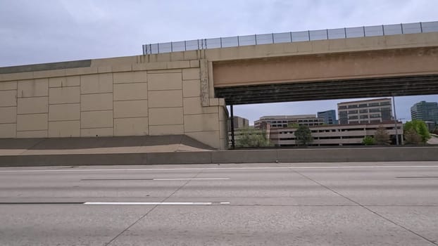 A dynamic view of the elevated highway overpass in South Denver, showcasing the intricate concrete structures and modern road design. The image captures the expansive lanes and surrounding landscape under a cloudy sky.