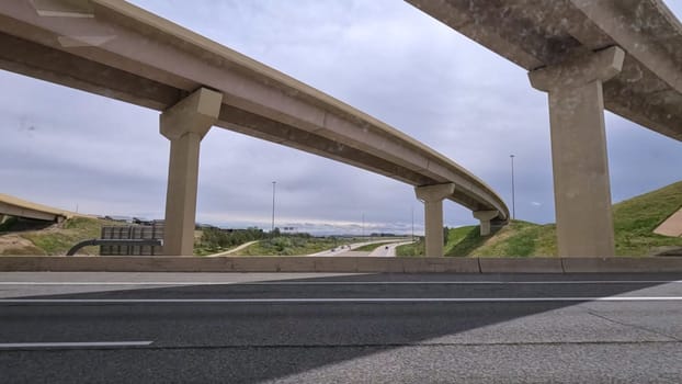 A dynamic view of the elevated highway overpass in South Denver, showcasing the intricate concrete structures and modern road design. The image captures the expansive lanes and surrounding landscape under a cloudy sky.