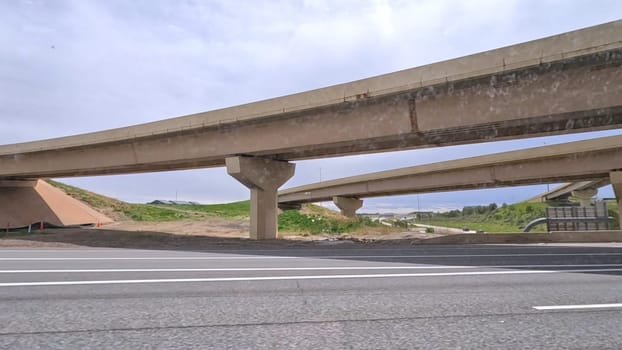 A dynamic view of the elevated highway overpass in South Denver, showcasing the intricate concrete structures and modern road design. The image captures the expansive lanes and surrounding landscape under a cloudy sky.