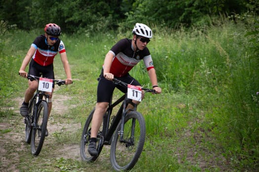 Kursk, Russia, June 15, 2024: Young guys on bicycles in turn at mountain bike competition fighting for position, cross-country cycling