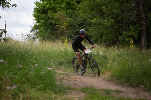 Kursk, Russia, June 15, 2024: Bike racer takes a turn on trail in forest at mountain bike competition