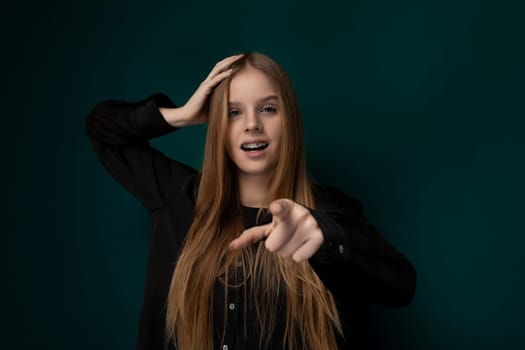 A woman with vibrant red hair is pointing directly at the camera, engaging the viewer with a confident expression. Her long red locks cascade down her shoulders, drawing attention to her gesture.