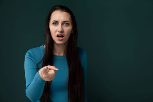 A woman with flowing long hair pointing at an unseen object, her arm extended and finger outstretched. She appears focused and engaged, highlighting the direction of her interest.