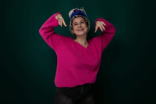 A young woman wearing a pink sweater is striking a pose for a photograph. She is standing and smiling in a confident manner, exuding a sense of poise and style.
