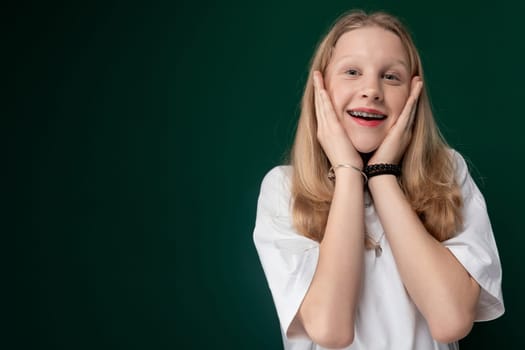 A young girl is standing and posing for a picture with her hands covering her face. She appears to be smiling and enjoying the moment.