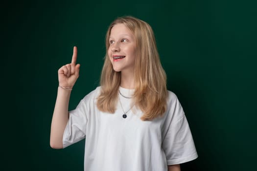 A woman wearing a white t-shirt is pointing at an object or direction. She appears engaged and focused on something while gesturing with her hand.