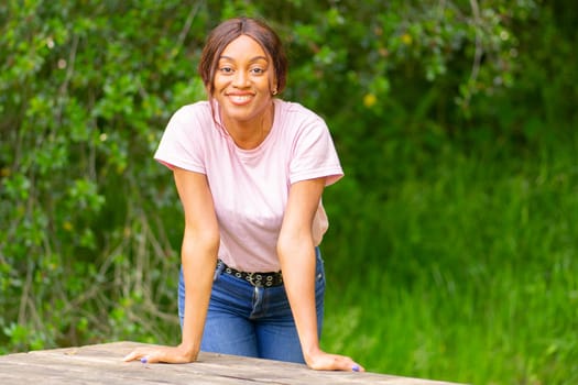 Young, beautiful black woman leaning on a bench in a park on an autumn afternoon.