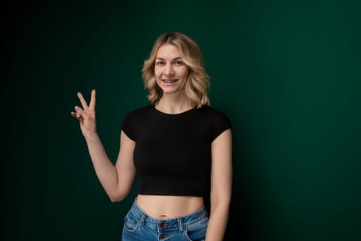 A woman is standing upright in front of a vibrant green wall, looking directly at the camera. She appears confident and composed.