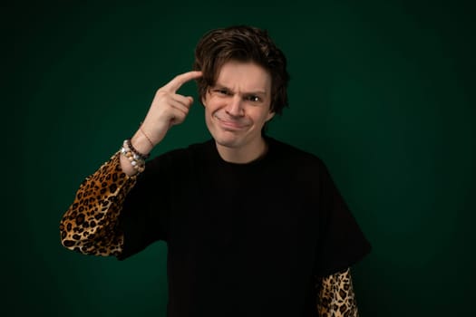 A man wearing a black shirt is extending his fingers to form a peace sign gesture. He is standing in a casual posture, with a neutral facial expression.