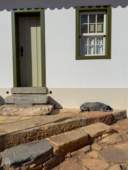 A dog peacefully naps on warm stone steps by a traditional house door.