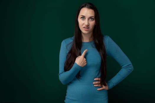 A woman with long brown hair wearing a blue shirt is smiling and giving a thumbs up gesture.
