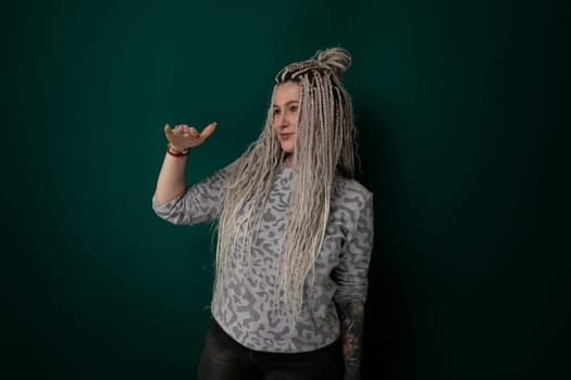 A woman with long hair is standing in front of a solid green wall. She is facing forward, with her hair cascading down her back. The wall provides a simple backdrop to highlight the womans presence.