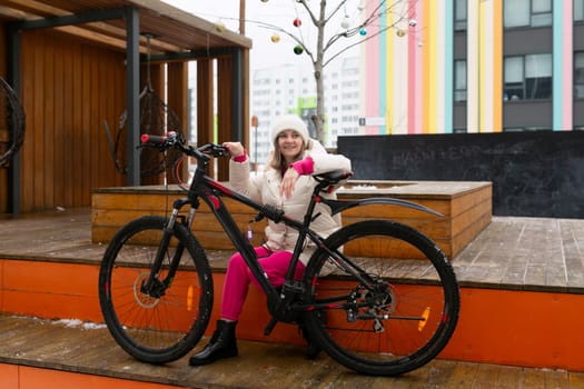 A woman is seated on a bench next to a bicycle. The scene shows a woman taking a break by resting on the bench while the bike stands beside her.