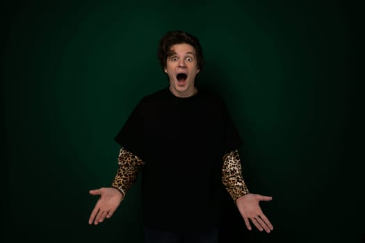 A man wearing a black shirt is standing with a surprised expression on his face. His eyes are wide open, and his mouth is slightly agape in astonishment.