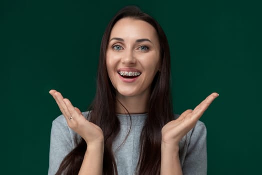 A woman is playfully contorting her face with her hands, creating a comical expression. Her hands are positioned near her eyes, nose, and mouth as she distorts her features.