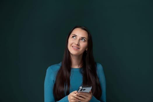 A woman is holding a cell phone in her hands, looking at the screen intently. She appears focused and engaged with the device, possibly texting or browsing the internet.