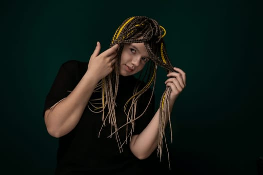 A woman with dreadlocks holding her hair in front of her face, partially obscuring her features. She is focused on her hair, which is styled in long, thick dreadlocks.