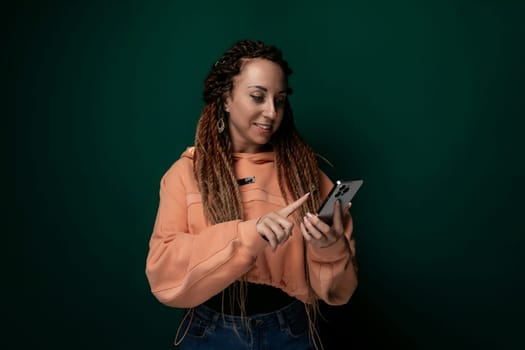 A woman with dreadlocks is using her cell phone. She is focused on the screen, tapping and scrolling. Her hair is styled in long, twisted dreadlocks. She appears engaged in whatever she is doing on the phone.